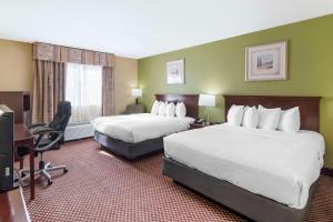 a hotel room with two beds and a desk at Quality Inn & Suites Bloomington University Area in Bloomington