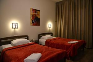Habitación de hotel con 2 camas con sábanas rojas en Iris Flower Hotel en Jezzîne