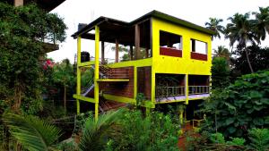 żółty domek na drzewie pośrodku ogrodu w obiekcie Dakshinamurthi Beach Stay w mieście Gokarna