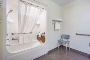 baño blanco con ducha y silla azul en Sleep Inn Sea Tac Airport en SeaTac