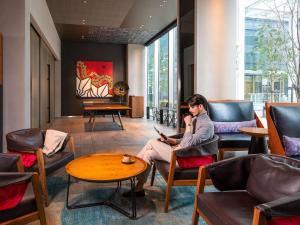 a woman sitting in a chair in a lobby with a laptop at Pullman Tokyo Tamachi in Tokyo