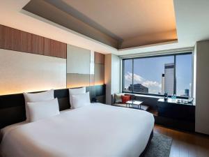 a bedroom with a large white bed and a large window at Pullman Tokyo Tamachi in Tokyo