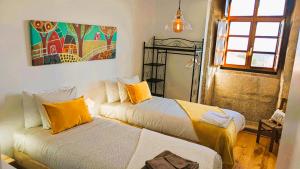 a bedroom with two beds and a painting on the wall at Lagarto Pintado Casa n'Aldeia in Castelo Novo