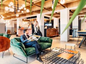 a man and woman sitting in a chair in a lobby at Novotel Parma Centro in Parma