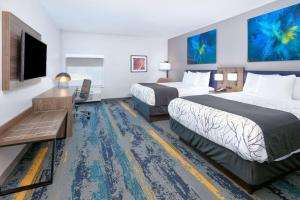 a hotel room with two beds and a flat screen tv at La Quinta Inn & Suites by Wyndham Dallas/Fairpark in Dallas