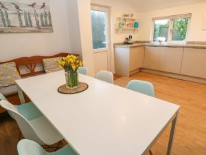 cocina y comedor con mesa blanca y sillas en Camellia en Penzance