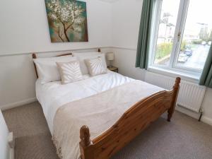 1 dormitorio con 1 cama con sábanas blancas y ventana en Camellia en Penzance
