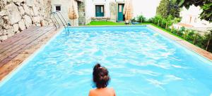 a woman is sitting in a swimming pool at Lagarto Pintado Casa n'Aldeia in Castelo Novo