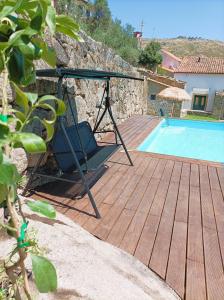 een schommel op een terras naast een zwembad bij Lagarto Pintado Casa n'Aldeia in Castelo Novo