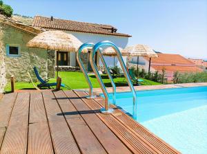 een houten terras met een glijbaan naast een zwembad bij Lagarto Pintado Casa n'Aldeia in Castelo Novo