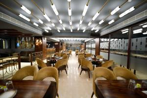 un ristorante con tavoli e sedie in legno e finestre di Hotel Palacio a Guwahati