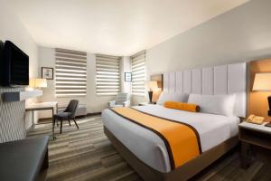 a hotel room with a large bed and a desk at Hotel Marguerite South Anaheim - Garden Grove, Trademark Collection by Wyndham in Anaheim