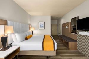 a hotel room with a bed and a flat screen tv at Hotel Marguerite South Anaheim - Garden Grove, Trademark Collection by Wyndham in Anaheim