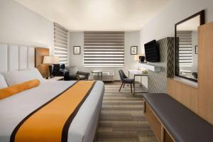 a hotel room with a bed and a living room at Hotel Marguerite South Anaheim - Garden Grove, Trademark Collection by Wyndham in Anaheim
