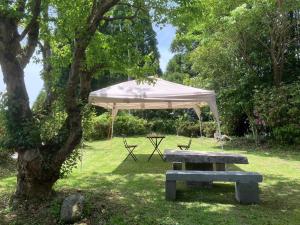 a picnic table and a tent in a park at Guesthouse Coco Garage in Kirishima