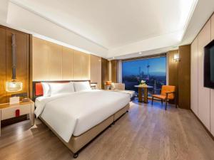 a large bedroom with a large white bed and a table at Swissôtel Shenyang in Shenyang