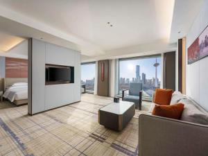a living room with a couch and a bed and a television at Swissôtel Shenyang in Shenyang