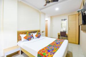 a bedroom with a large white bed with colorful sheets at FabHotel Royal Empire - Bird Valley Udhyan in Chinchiwad