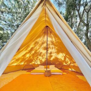 une tente jaune et blanche avec des arbres en arrière-plan dans l'établissement Glamping on Organic Yoga Farm with Natural Swimming Pool near Beach, à Moncarapacho