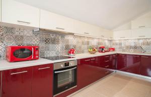 cocina con armarios rojos y microondas rojo en Casa di Cuore - Beachfront, en Argassi