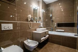 a bathroom with a toilet and a sink and a tub at Barack Thermal Hotel and Spa in Tiszakécske