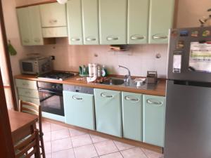 una cucina con armadi bianchi, lavandino e frigorifero di Enza-home-in-ROMA a Borghesiana