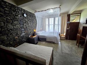 um quarto com uma cama e uma parede de pedra em Dorala Villa-Your home away home em Kuruwita