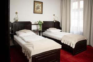 a room with two beds and a table in it at Hotel Dwór Polski in Wrocław