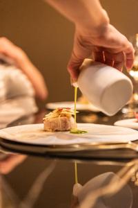 uma pessoa a deitar comida num prato sobre uma mesa em Hotel De Barrier em Aan de Wolfsberg