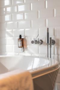 a bathroom with a sink and white tiles at Hotel De Barrier in Aan de Wolfsberg