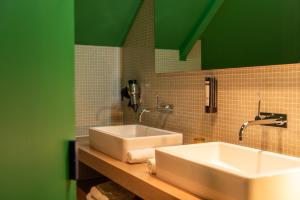 Aan de WolfsbergにあるHotel De Barrierの緑の壁のバスルーム(シンク2台付)
