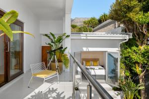 a balcony with a bed and chairs and plants at Agapanthus 8 in Cape Town