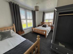 a bedroom with two beds and two windows at The Queens Hotel Harlech in Harlech