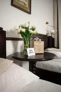 a table with a vase of white flowers on it at Hotel Dwór Polski in Wrocław