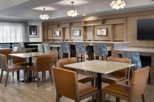 Fairfield by Marriott Inn & Suites Fresno Riverpark في فريسنو: غرفة طعام بها طاولات وكراسي وتلفزيون بشاشة مسطحة