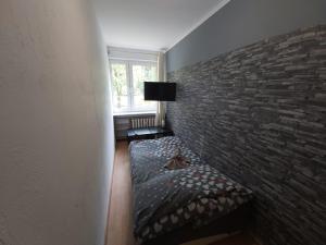 Cette chambre dispose d'un lit avec un mur en briques. dans l'établissement 2050 Zwycięstwa 23 - Tanie Pokoje - samodzielne zameldowanie - self check in, à Poznań