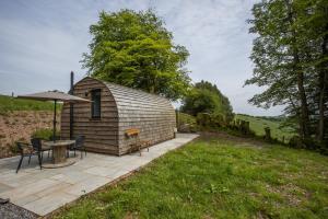 a small cabin with a table and chairs and an umbrella at Little House in the Big Woods Brendon Hill in Watchet