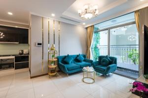 sala de estar con 2 sillas azules y cocina en VINHOMES LANDMARK CONDOTEL SUITE en Ho Chi Minh