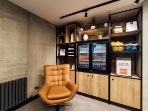 una sedia arancione in una stanza con un refrigeratore per bevande di ibis Coleraine Riverside a Coleraine