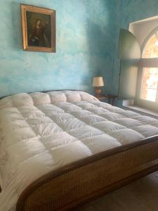 un grande letto in una camera da letto con un dipinto sul muro di Casale San Francesco Casa Pernicoló a Cirò