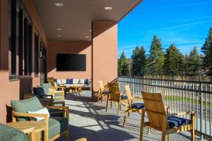 einen Balkon mit Stühlen und Tischen sowie einen Flachbild-TV in der Unterkunft The Hoffmann Hotel Basalt Aspen Tapestry Collection Hilton in Basalt