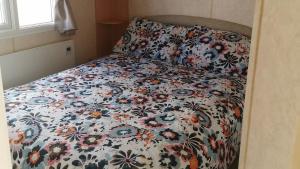 3-Bed 8 berth static caravan in ingoldmells في سكيجنيس: سرير مع لحاف الزهور في غرفة النوم