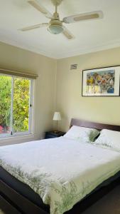 a bedroom with a bed with a ceiling fan and a window at COMFORT QUEEN GARDEN VIEW ROOM MACQUARIE PARK RYDE in Sydney