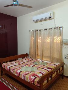 een slaapkamer met een bed met een gordijn en een raam bij Maria Vilas in Tirunelveli