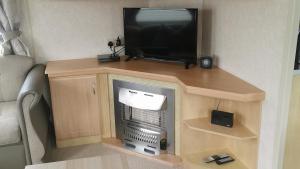 una TV seduta sopra un supporto con camino di 3-Bed 8 berth static caravan in ingoldmells a Skegness
