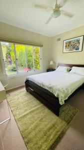 a bedroom with a bed with a rug and windows at COMFORT QUEEN GARDEN VIEW ROOM MACQUARIE PARK RYDE in Sydney