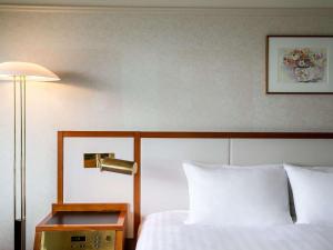 a hotel room with a bed and a lamp at Grand Mercure Nasu Highlands Resort & Spa in Nasu
