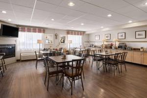 a dining room with tables and chairs and a kitchen at Travelodge by Wyndham Fort McMurray in Fort McMurray