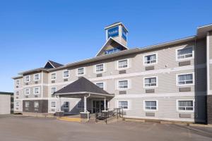 un gran edificio blanco con un cartel encima en Travelodge by Wyndham Fort McMurray en Fort McMurray