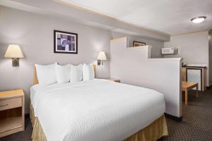 a hotel room with a large white bed and a desk at Travelodge by Wyndham Fort McMurray in Fort McMurray